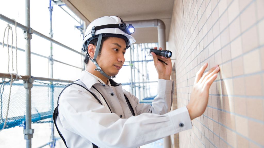 マンション外壁タイルを点検している作業員